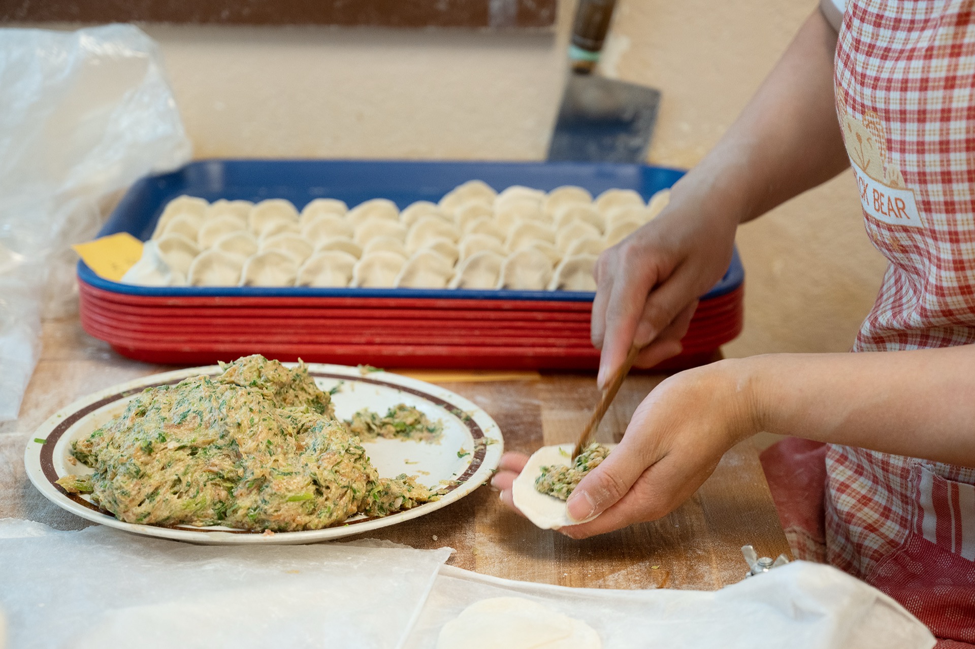 用筷子從盤中取餡填入餃子皮